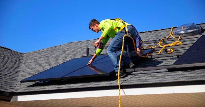 how is solar panel made - this image show a guy on a roof installing a panel for solar energy